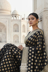 Woman in a black and gold Banarasi Georgette saree in front of the Taj Mahal.
