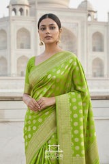 Woman wearing a lime-green Banarasi georgette saree with motif patterns in front of Taj Mahal.