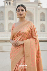 Woman in a peach Banarasi georgette silk saree with gold polka patterns standing in front of the Taj Mahal.
