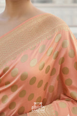 Coral saree with gold polka dots and border, featuring the brand 'Banarsi'.