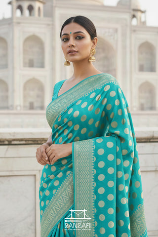 Woman in a firozi blue Banarasi georgette silk saree with gold polka patterns standing in front of the Taj Mahal.