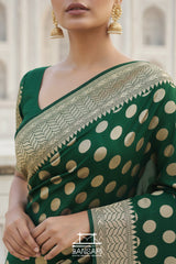 Green saree with gold polka dots and intricate border, worn by a model.