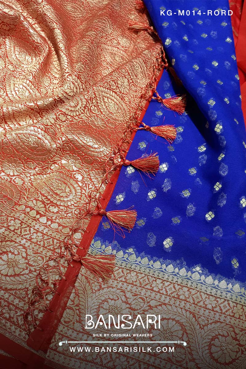Close-up of a red and blue georgette saree with intricate patterns and tassels, featuring the brand 'Bansari'.
