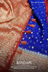 Close-up of a red and blue georgette saree with intricate patterns and tassels, featuring the brand 'Bansari'.